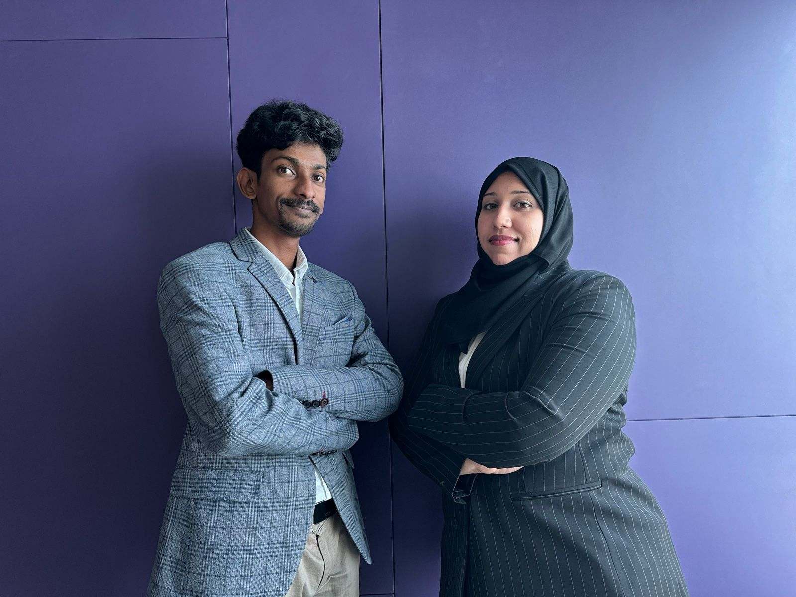 Two Missan team members with arms folded against a purple wall
