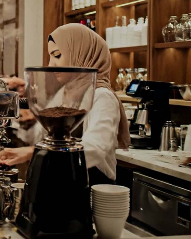 Frame from the Bina film: a barista making coffee behind a busy café counter on a Friday night