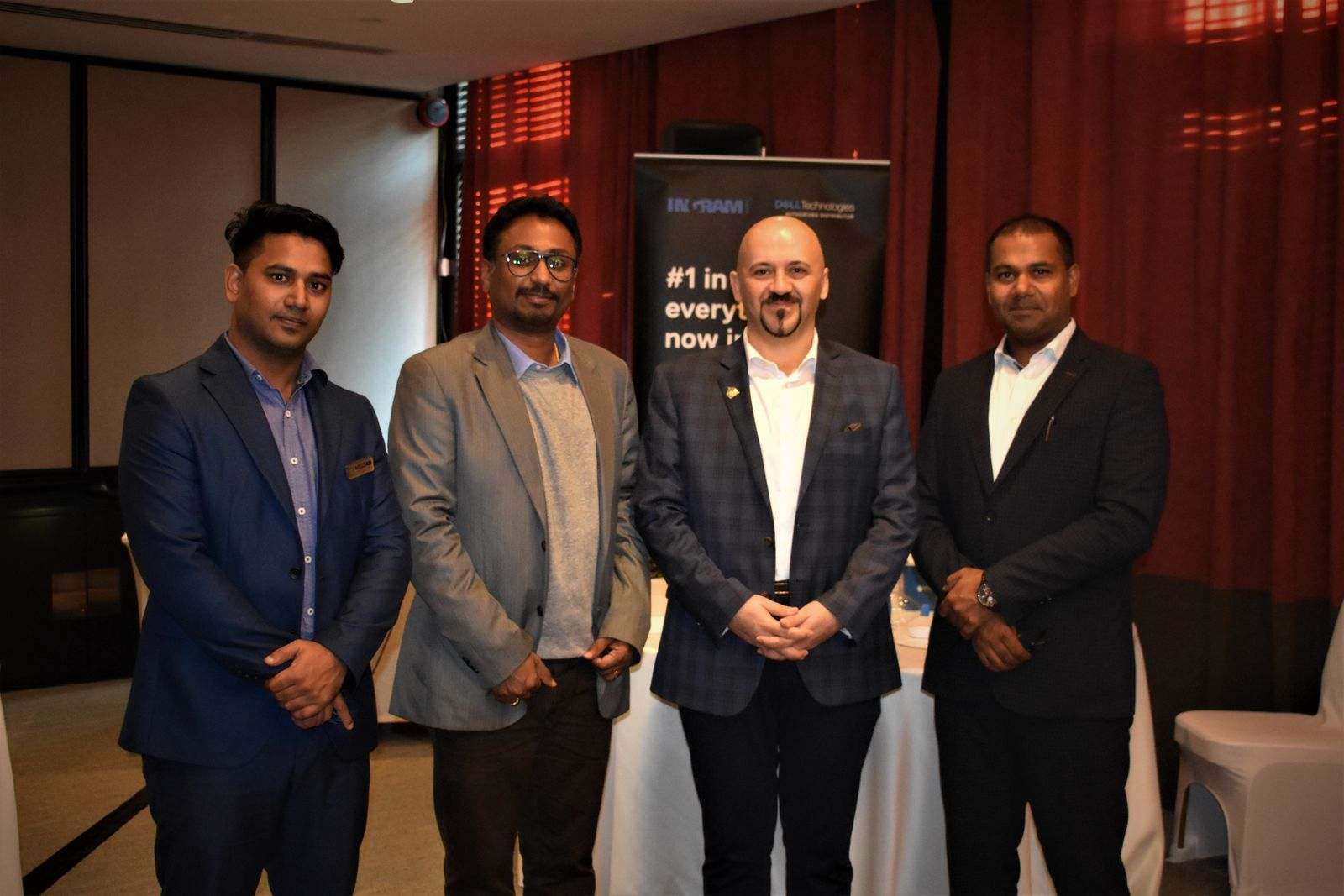 Four men in suits beside an Ingram Micro and Dell Technologies banner
