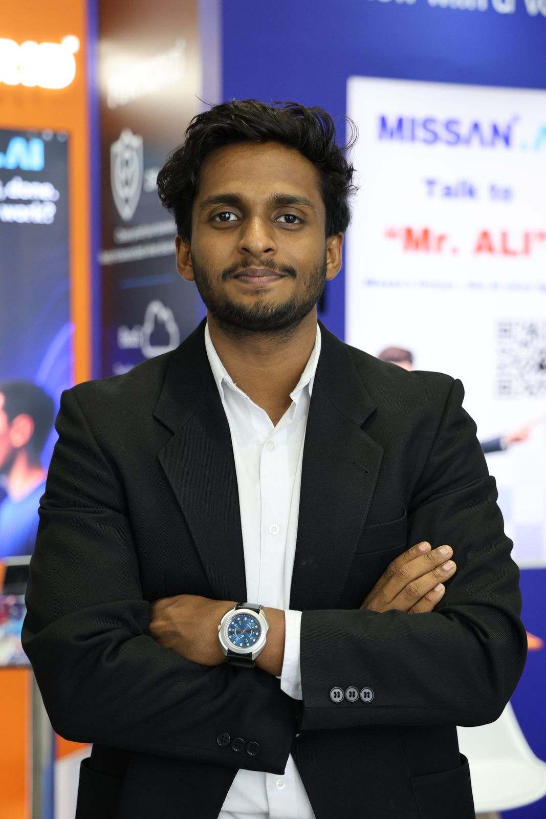 A Missan team member in a black suit, arms crossed, in front of the Missan.AI panel