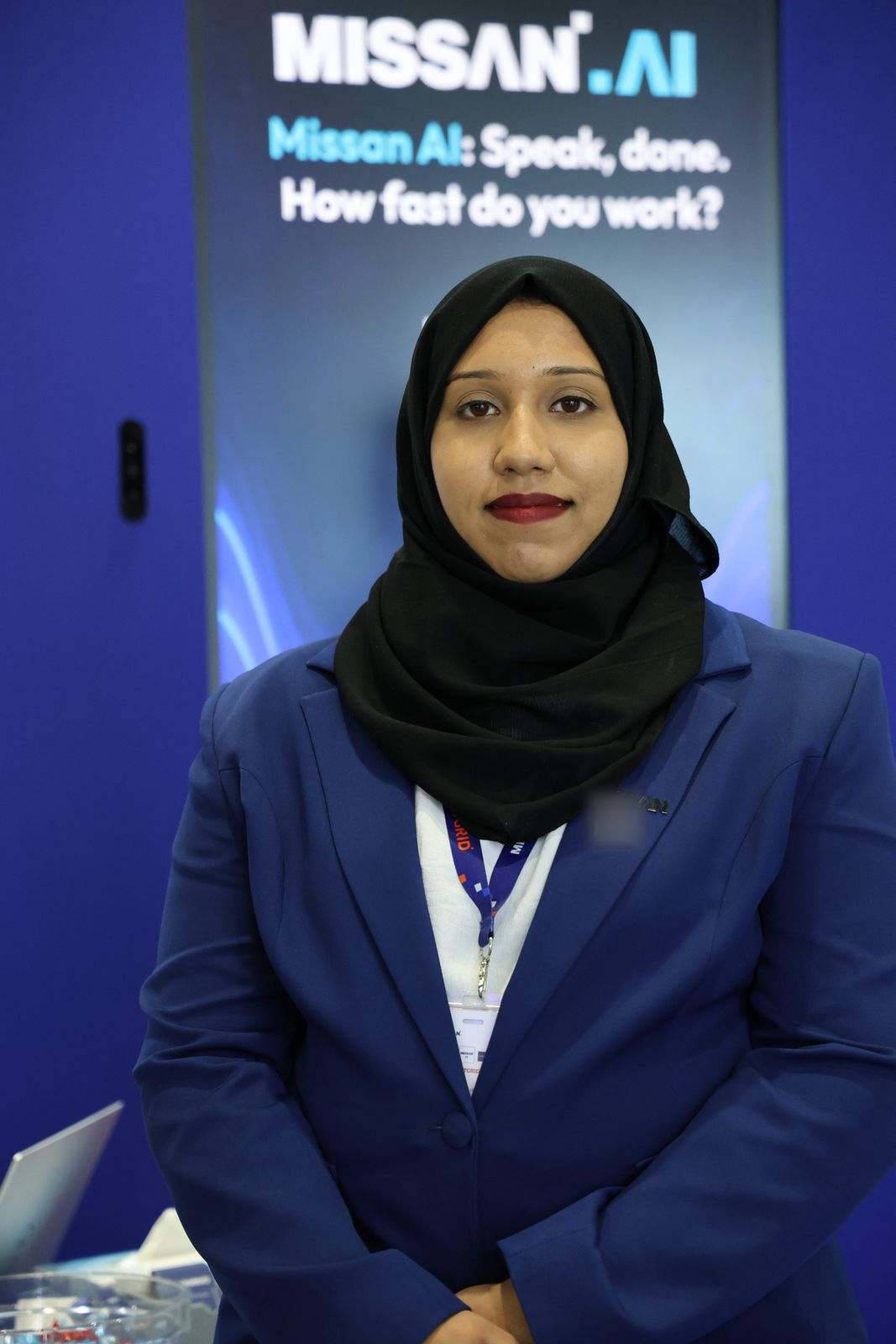 A Missan team member in a navy blazer and hijab in front of the Missan.AI screen
