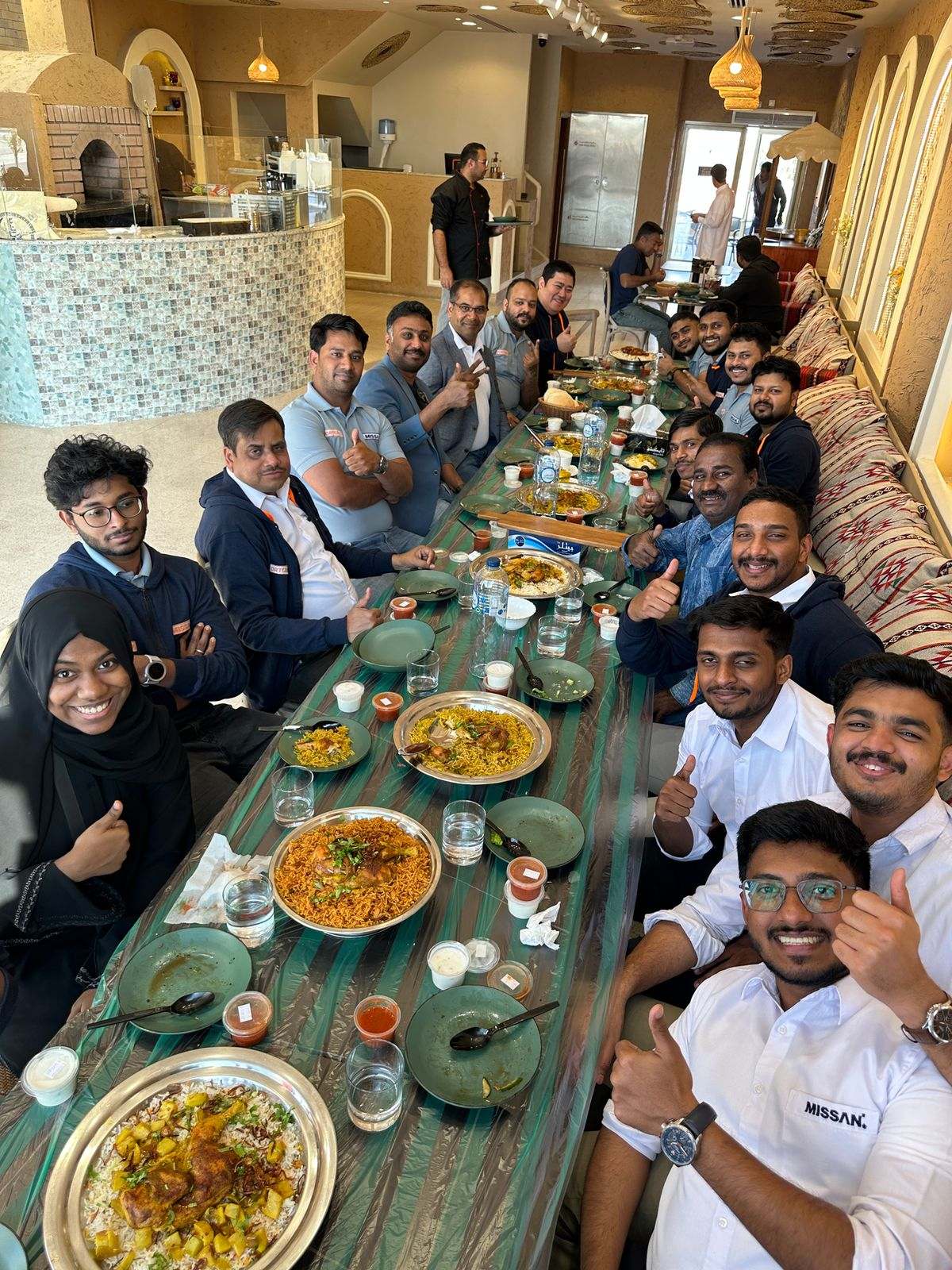 About twenty Missan staff along a long restaurant table giving a thumbs up